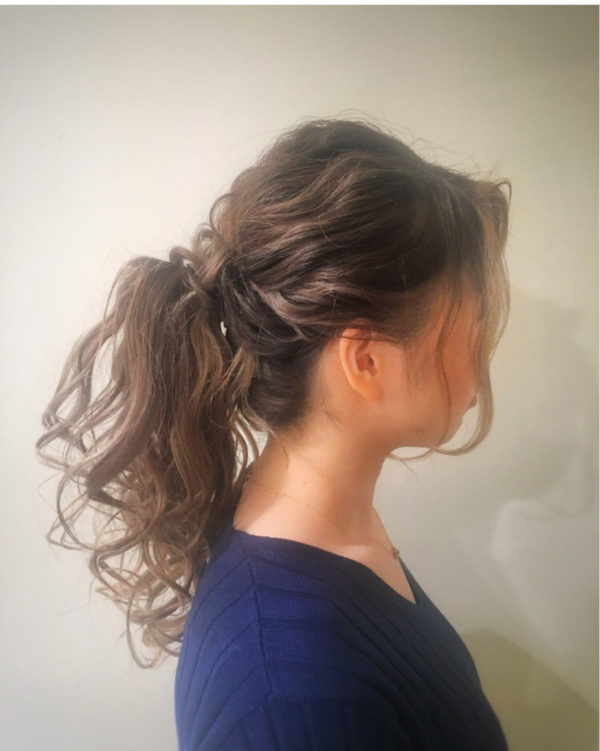 巻いた髪をくしゅくしゅっと無造作に結んだヘアアレンジ。タイトにまとめるとポニーテールは学生っぽくなりがちなので、ふわふわ感のボリュームを大事にして。