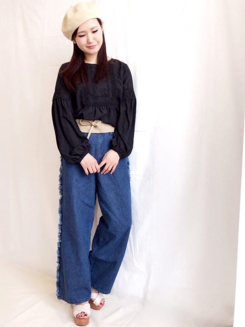 サイドのフリンジがヒッピーライクなワイドデニムにガーリーシックな黒のブラウスを合わせたミックスコーデ。