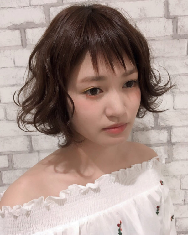 バングのはっきりとしたぎざぎざが、パーマとの組み合わせで甘辛MIXになり、愛されヘアに。